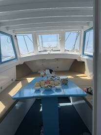 Interior view of a boat's dining area featuring a blue table set with an array of food and drinks, perfect for onboard meals and gatherings.
