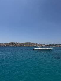 A sleek speedboat anchored in crystal-clear turquoise waters, surrounded by rocky shores — perfect for a day of relaxation on the water.