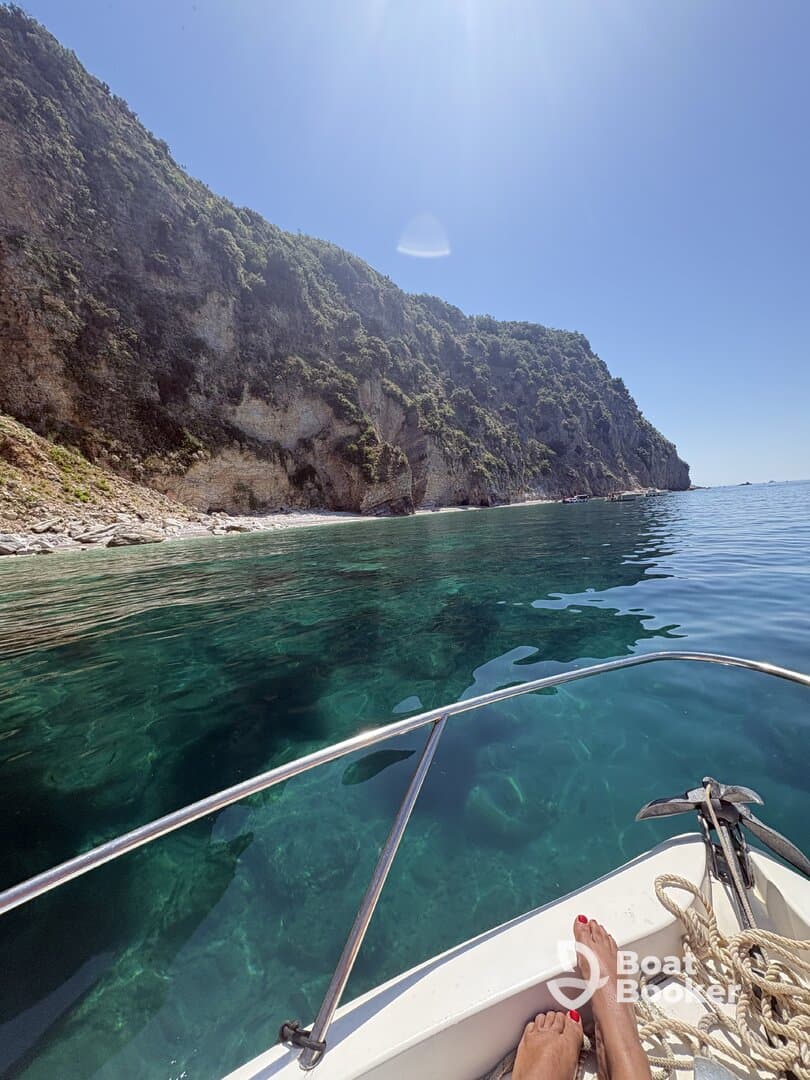 A serene view from the bow of a boat, showcasing the stunning coastline and crystal-clear waters — perfect for a relaxing day on the water.