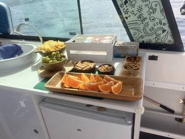 A beautifully arranged spread of snacks including grapes, chips, and oranges on a boat, perfect for enjoying while cruising on the water.