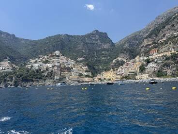 A stunning view of the picturesque coastal town of Positano, nestled among the cliffs of the Amalfi Coast, showcasing vibrant buildings and serene waters — a perfect destination for boat tours and scenic cruises.