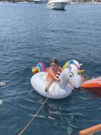 A joyful child enjoys a sunny day on a unicorn float in the water, capturing the essence of summer fun and family adventures.