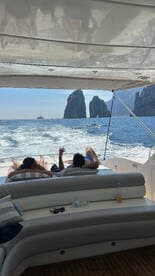 Guests relax on the deck of a yacht while enjoying stunning views of the iconic rock formations in Cabo, creating the perfect backdrop for a memorable day on the water.