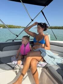 A mother and her young daughter relax inside the boat, enjoying a sunny day on the water. The cozy seating area provides a perfect spot for family bonding during their boating adventure.