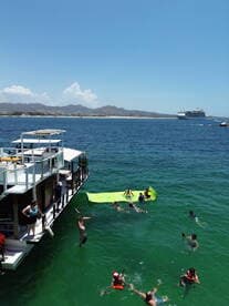 A lively group enjoys a fun day in the water, with people jumping off a boat and engaging in various activities — perfect for summer adventures and family outings.