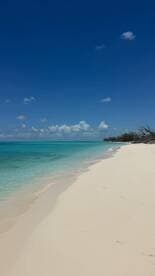A stunning view of a pristine beach with soft white sand and crystal-clear turquoise waters, perfect for a relaxing getaway or beach day.