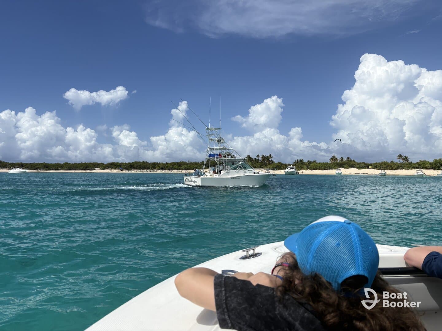 A scenic view of a fishing boat cruising through turquoise waters, with a beach in the background and a child enjoying the ride — perfect for family adventures on the water.