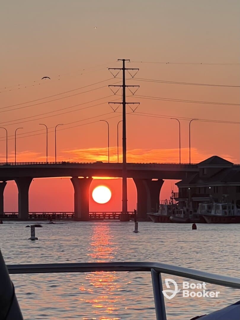 A stunning sunset view framed by a bridge, captured from the deck of a boat — perfect for evening cruises and scenic photography.