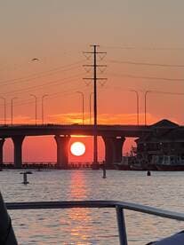 A stunning sunset view framed by a bridge, captured from the deck of a boat — perfect for evening cruises and scenic photography.