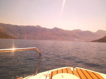 A scenic view from the bow of a boat, showcasing the stunning mountainous landscape and calm waters, perfect for exploring coastal destinations.