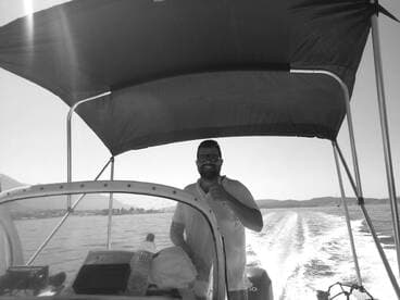 A cheerful individual gives a thumbs up while steering a boat, capturing the joy of a day on the water.