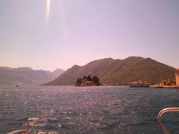 A picturesque view of an island surrounded by mountains, showcasing the stunning coastline and tranquil waters — an ideal destination for scenic boat tours.