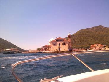 A scenic view of a historic landmark on the coastline, with visitors enjoying the vibrant atmosphere from a boat — a perfect representation of island exploration.