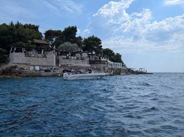 A scenic view of a boat cruising near a coastal restaurant, showcasing the beautiful shoreline and inviting atmosphere for a perfect day on the water.