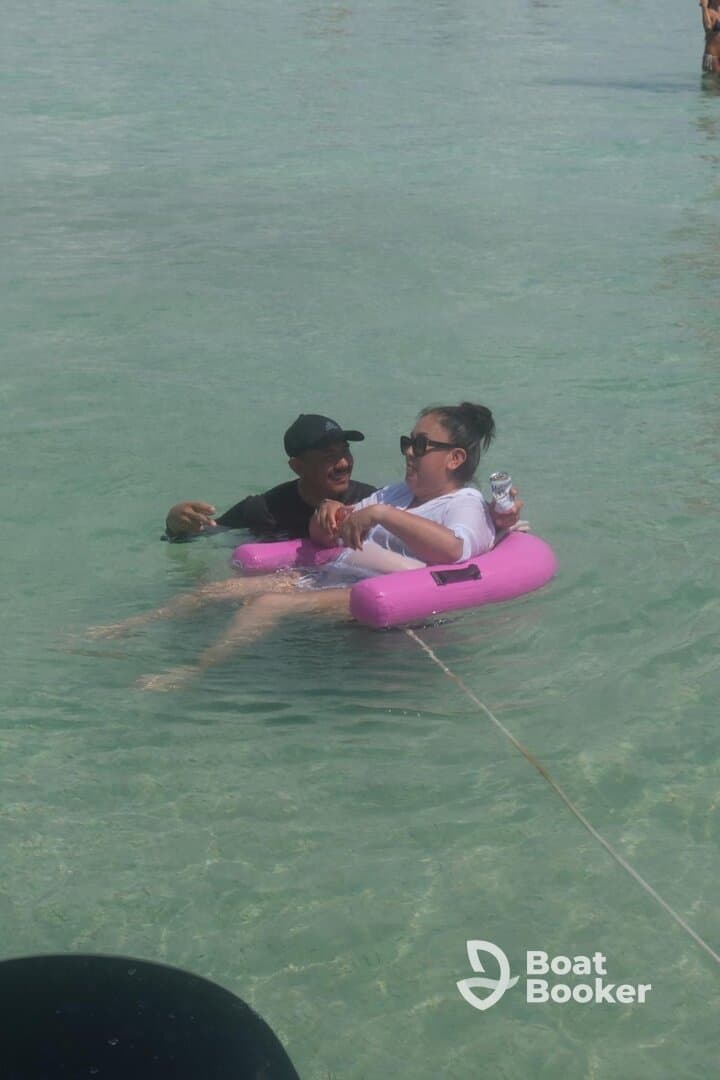 Two friends enjoy a fun day floating in the clear waters, capturing the essence of a perfect beach outing.