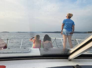 A group of friends enjoys the scenic view from the bow of a boat, capturing the essence of a perfect day on the water.