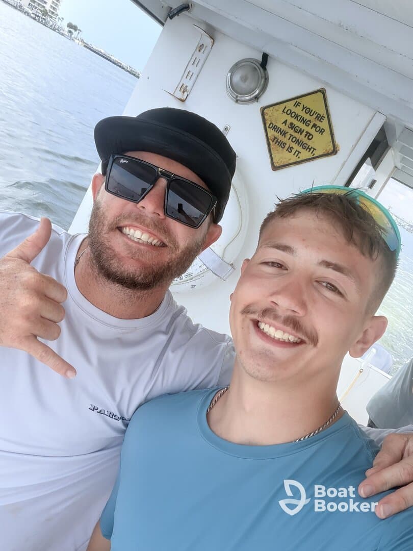 Two friends pose for a cheerful selfie on a boat, showcasing the fun and camaraderie of a day on the water.