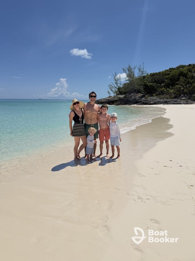 A joyful family poses together on a beautiful beach, surrounded by turquoise waters and soft sand — a perfect snapshot of their tropical vacation.