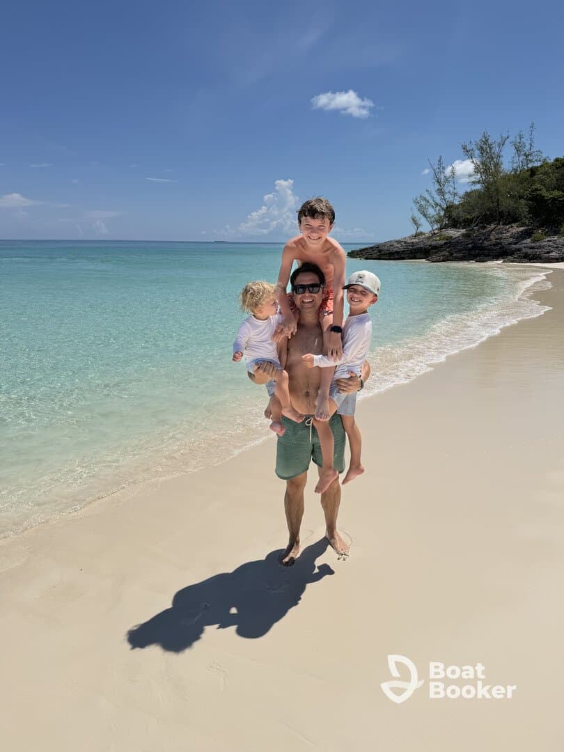 A joyful family moment on the beach, with a father playfully carrying his children — a perfect snapshot of fun and togetherness in a tropical paradise.