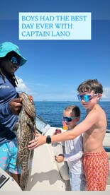 Two boys celebrate their catch with Captain Lano while fishing on a boat — a memorable day on the water filled with excitement and adventure.