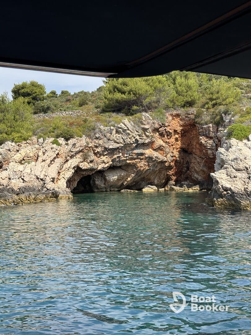 A picturesque view of a rocky coastline featuring a cave, captured from a boat — a serene moment showcasing the natural beauty of the area.