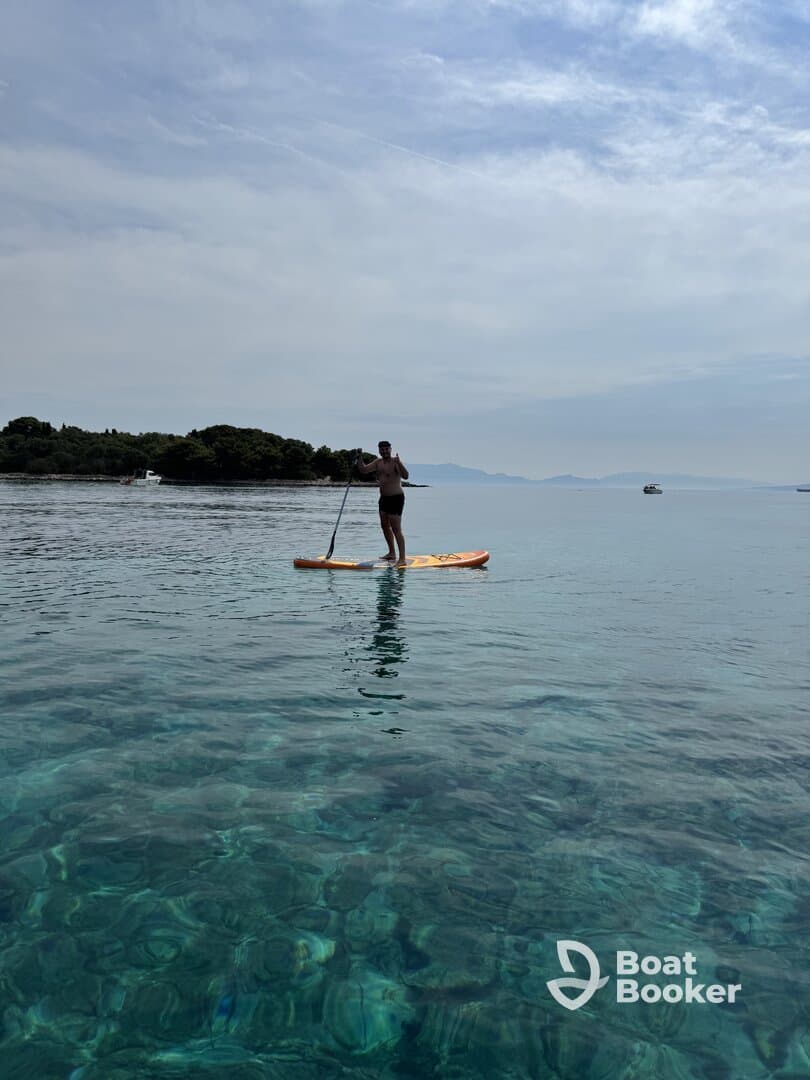 A paddleboarder enjoys the serene waters, showcasing the beauty of clear turquoise depths — perfect for water sports enthusiasts.
