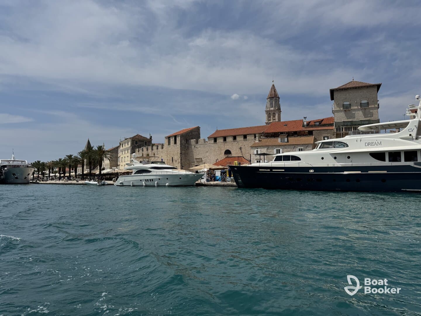 A picturesque view of luxurious yachts docked at a charming harbor, showcasing the beautiful coastal architecture and vibrant palm trees.