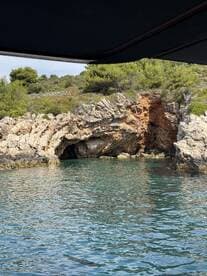 A picturesque view of a rocky coastline featuring a cave, captured from a boat — a serene moment showcasing the natural beauty of the area.