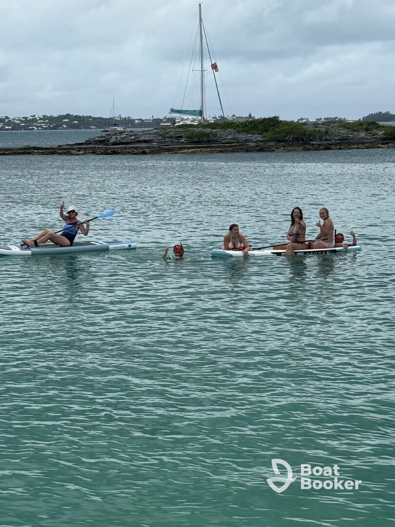 A lively group enjoys paddleboarding and swimming in clear waters, showcasing the fun of island hopping adventures.