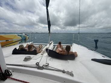 A group of friends relaxes on the deck of a catamaran, enjoying the ocean breeze and stunning views — perfect for a day of leisure on the water.