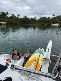 Two friends enjoy paddleboarding and swimming in calm waters, creating a perfect day of fun and relaxation on the water.