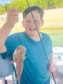 A joyful child proudly displays his catch while fishing on a boat, capturing the excitement of outdoor adventures and family fun on the water.