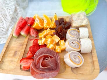 A beautifully arranged charcuterie board featuring fresh fruits, meats, and cheeses, perfect for enjoying onboard during a relaxing day at sea.