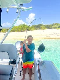 Two kids enjoy a fun fishing experience aboard a boat, showcasing the excitement of water activities in a beautiful setting.