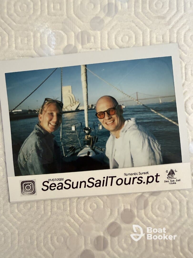 A couple enjoys a romantic sunset sailing experience, capturing a joyful moment on the water with the iconic backdrop of a bridge.
