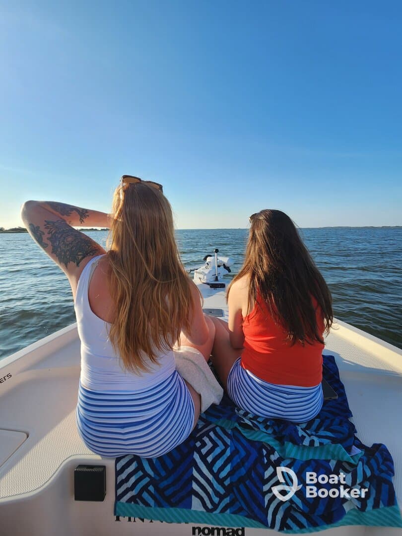 Two friends enjoy a sunny day on a boat, taking in the beautiful water views — a perfect moment for relaxation and camaraderie.