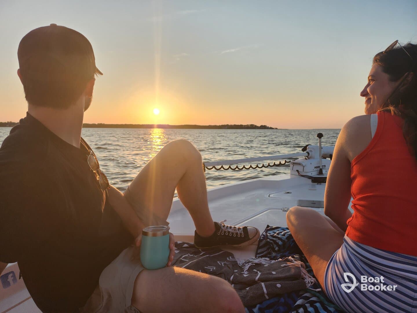 A couple enjoys a serene sunset view from their boat, creating a perfect romantic atmosphere on the water.