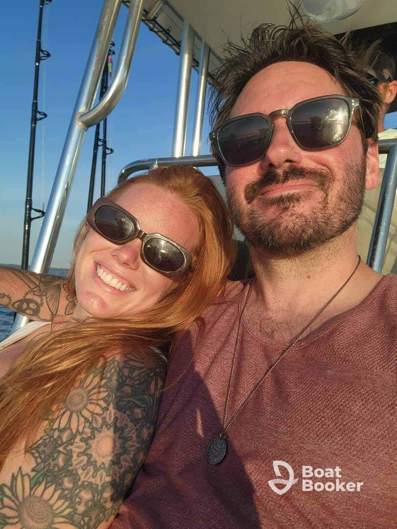 A happy couple enjoys a moment together on a boat, capturing the joy of their adventure under the warm glow of sunset.