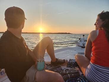 A couple enjoys a serene sunset view from their boat, creating a perfect romantic atmosphere on the water.