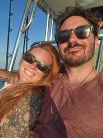 A happy couple enjoys a moment together on a boat, capturing the joy of their adventure under the warm glow of sunset.