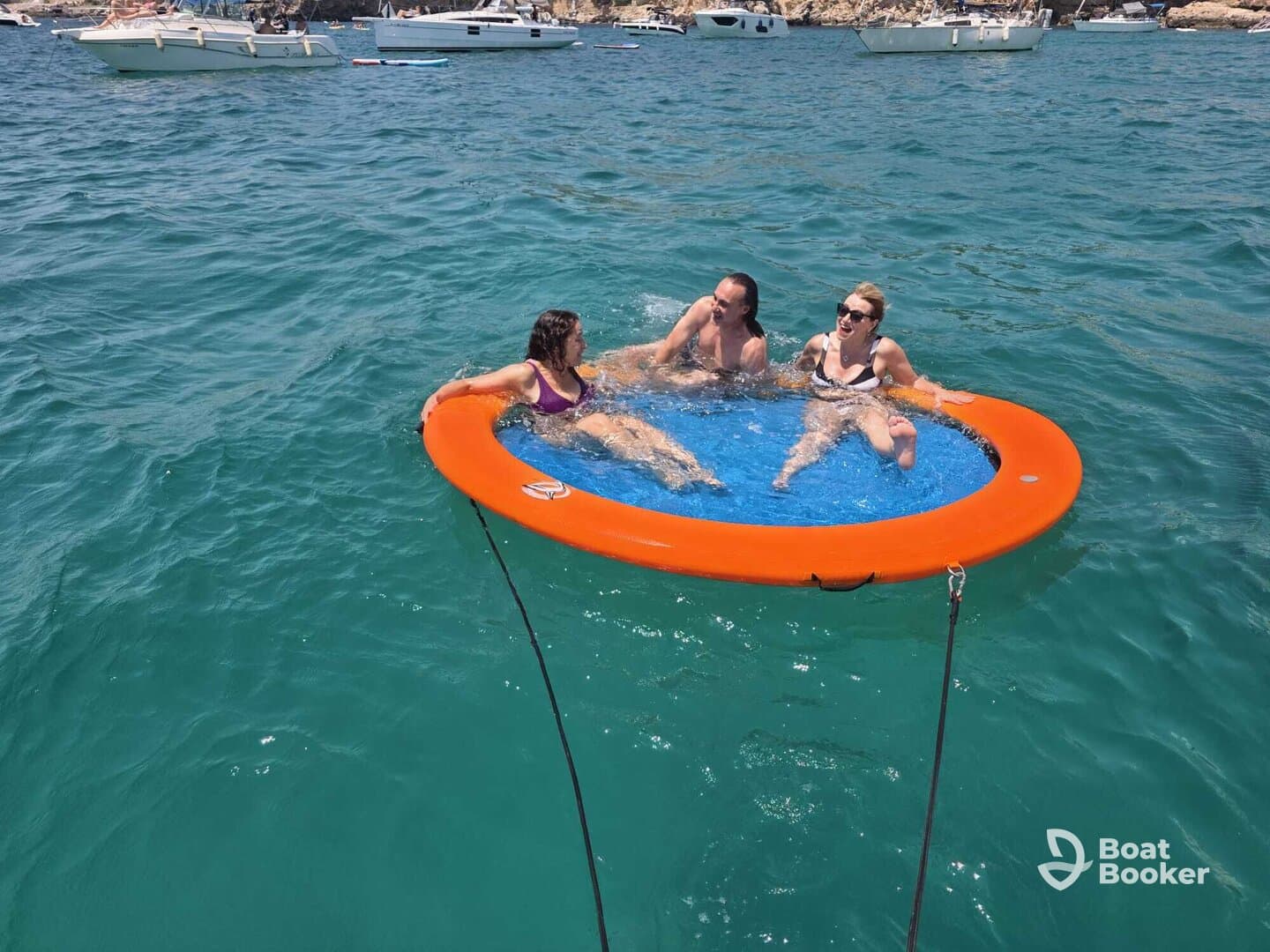 A fun group enjoys a sunny day on a floating mat in crystal-clear waters, perfect for relaxation and summer adventures.