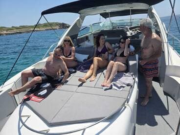 A lively group enjoys sunbathing on the deck of a yacht, capturing the essence of a perfect day on the water with friends.