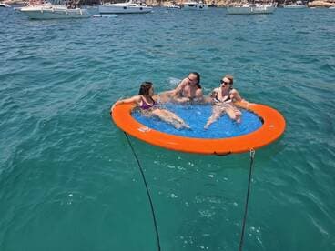 A fun group enjoys a sunny day on a floating mat in clear turquoise waters, perfect for relaxation and summer adventures.