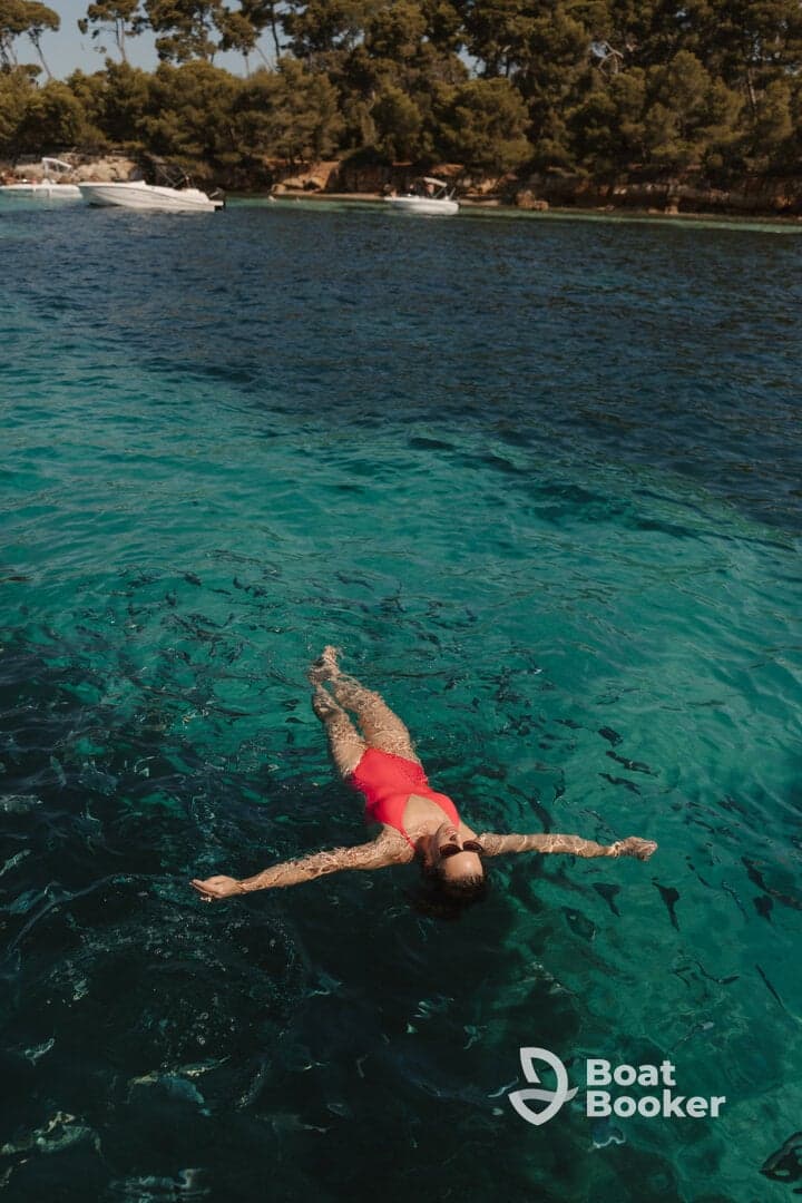 A woman floats serenely in crystal-clear waters, enjoying a perfect day of swimming and relaxation under the sun.