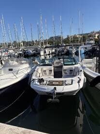 A sleek speedboat docked at a marina, surrounded by masts of sailboats, showcasing the vibrant boating scene.