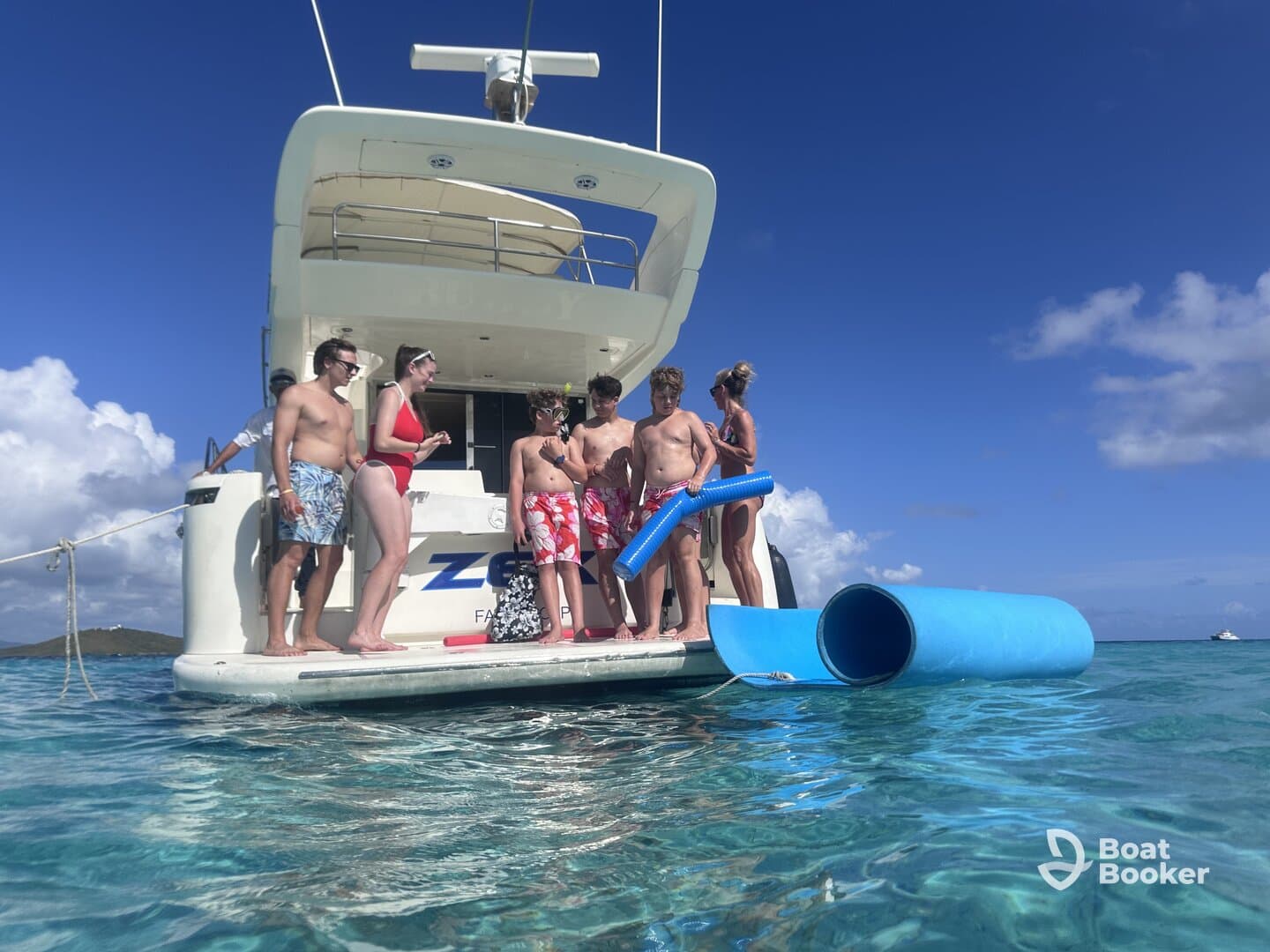 A lively group of friends and family enjoys a fun day on the water, preparing to slide into the ocean from their boat — perfect for summer adventures and family outings.