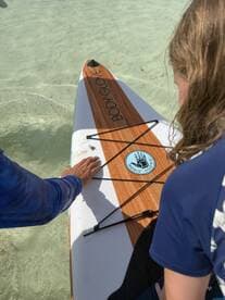 A close-up of a child and an adult interacting while paddleboarding, showcasing a moment of connection on the water — perfect for family adventures and water sports enthusiasts.