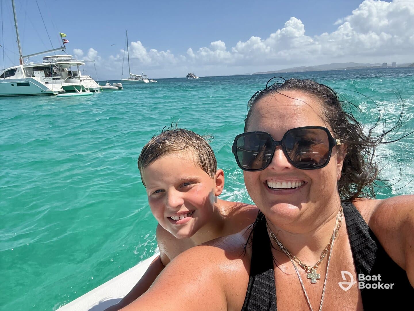 A joyful moment captured as a mother and her son enjoy a fun day on the water, with a catamaran in the background — perfect for family adventures and memorable experiences.