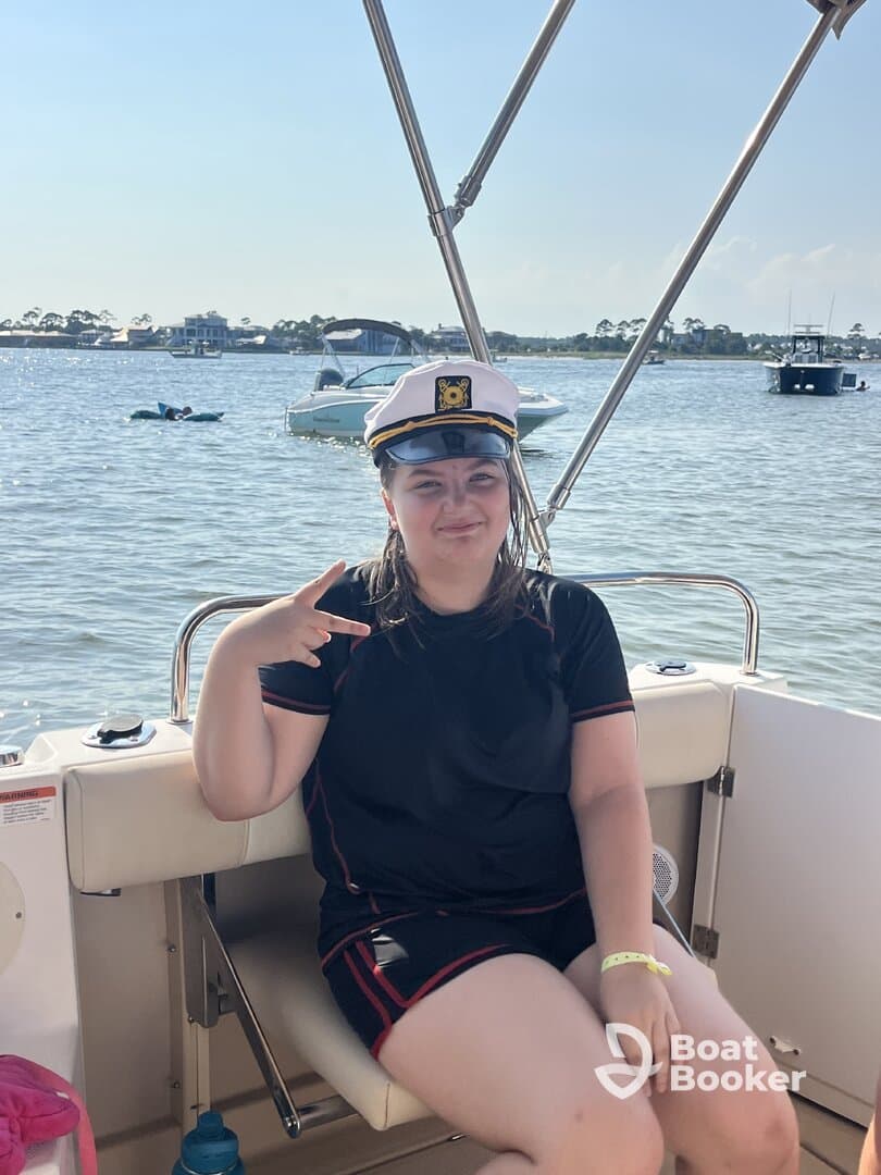 A young girl poses playfully in a captain's hat on a boat, capturing a fun moment during a day on the water — perfect for family outings and celebrations.