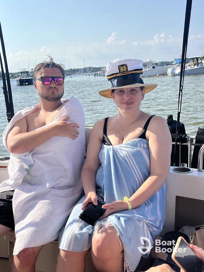 A couple enjoys a sunny day on a boat, showcasing a relaxed atmosphere with playful hats and towels — perfect for summer outings on the water.